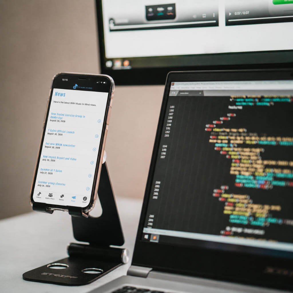 Smartphone interface displayed beside a laptop during mobile application development